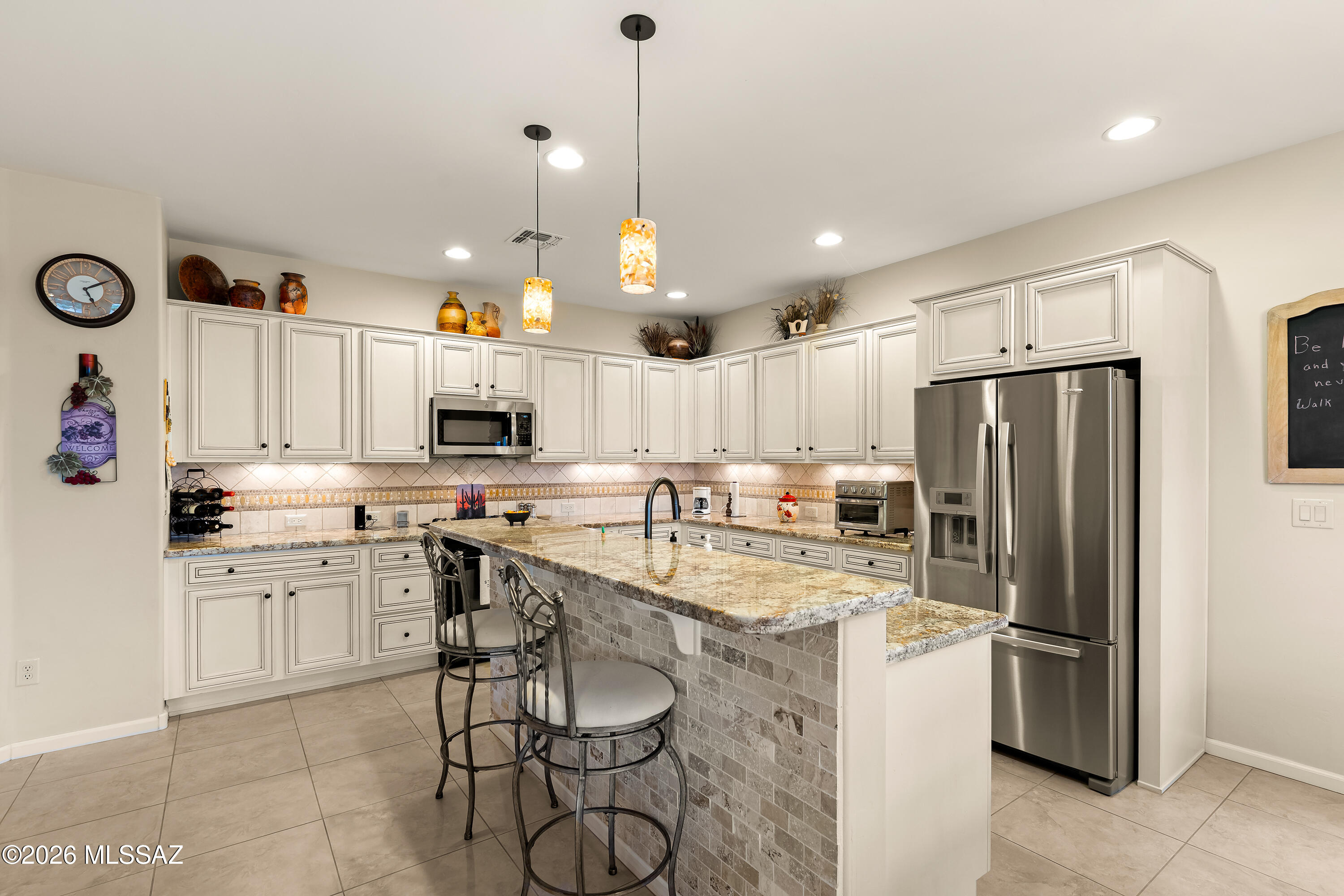 Kitchen with a granite-topped island, white cabinetry, and stainless-steel appliances.