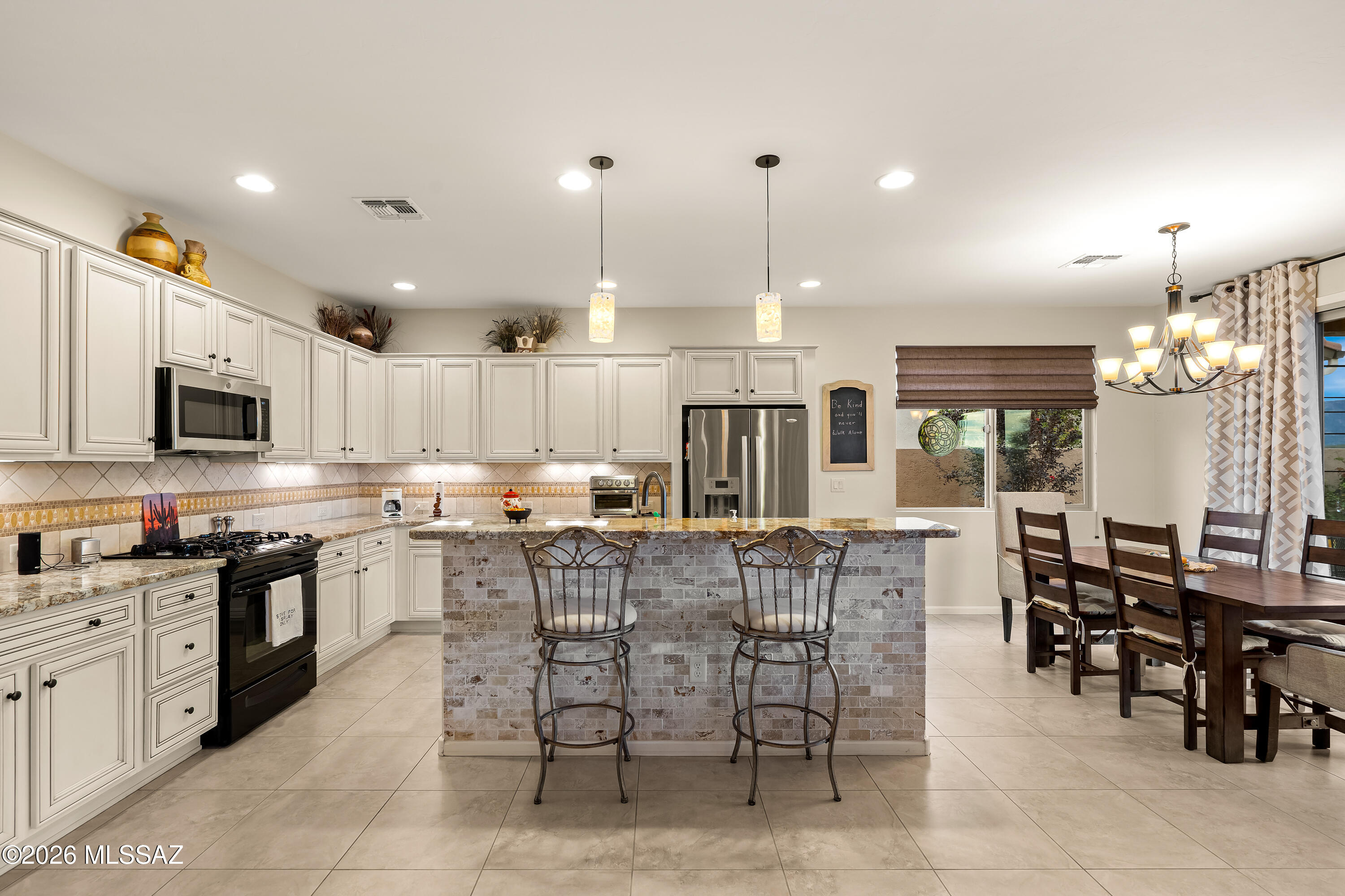 Kitchen with white cabinetry, tiled island, stainless steel appliances, and an adjoining dining area