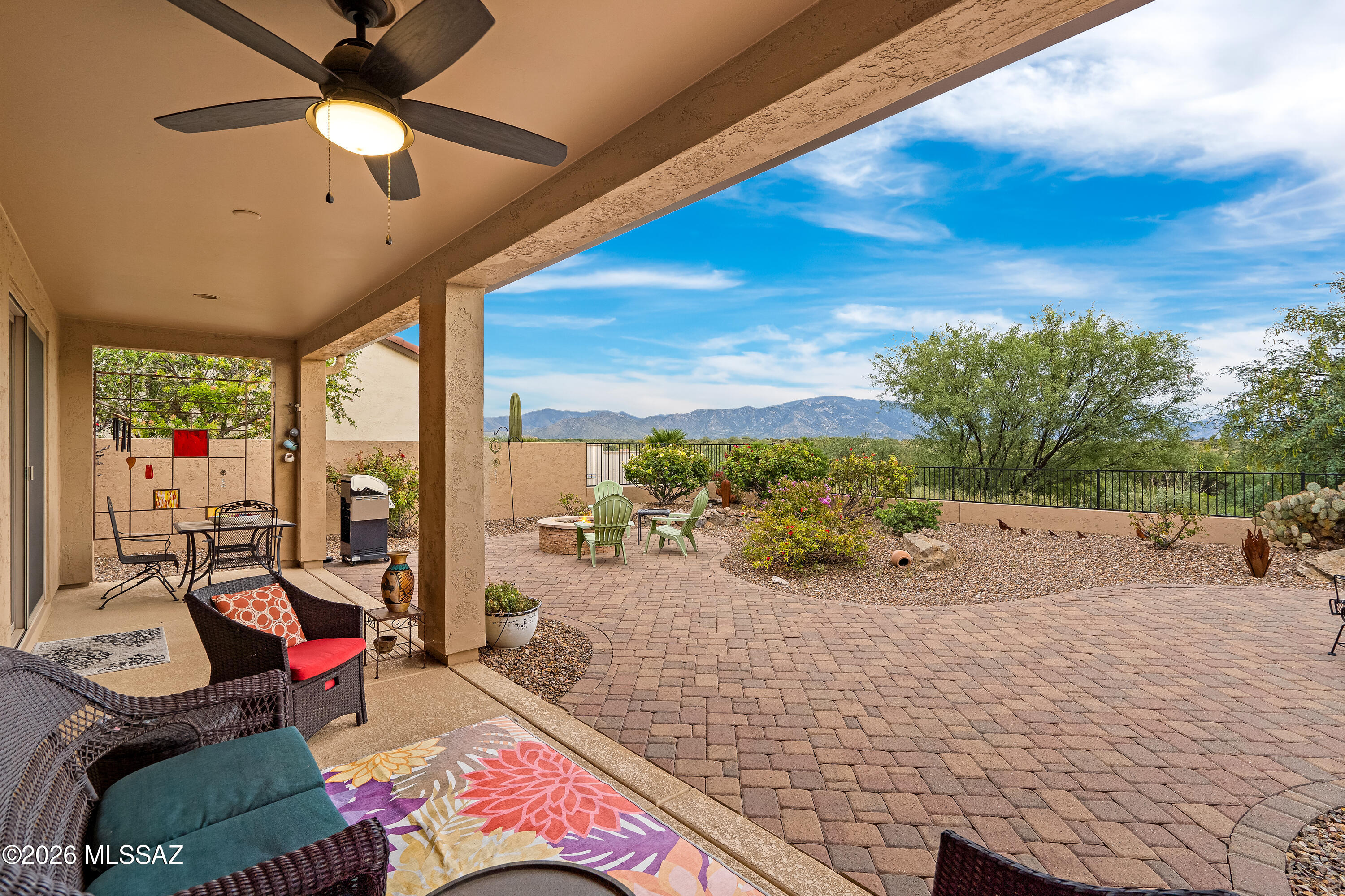 Covered patio and paver courtyard with outdoor seating, desert landscaping, and mountain views.