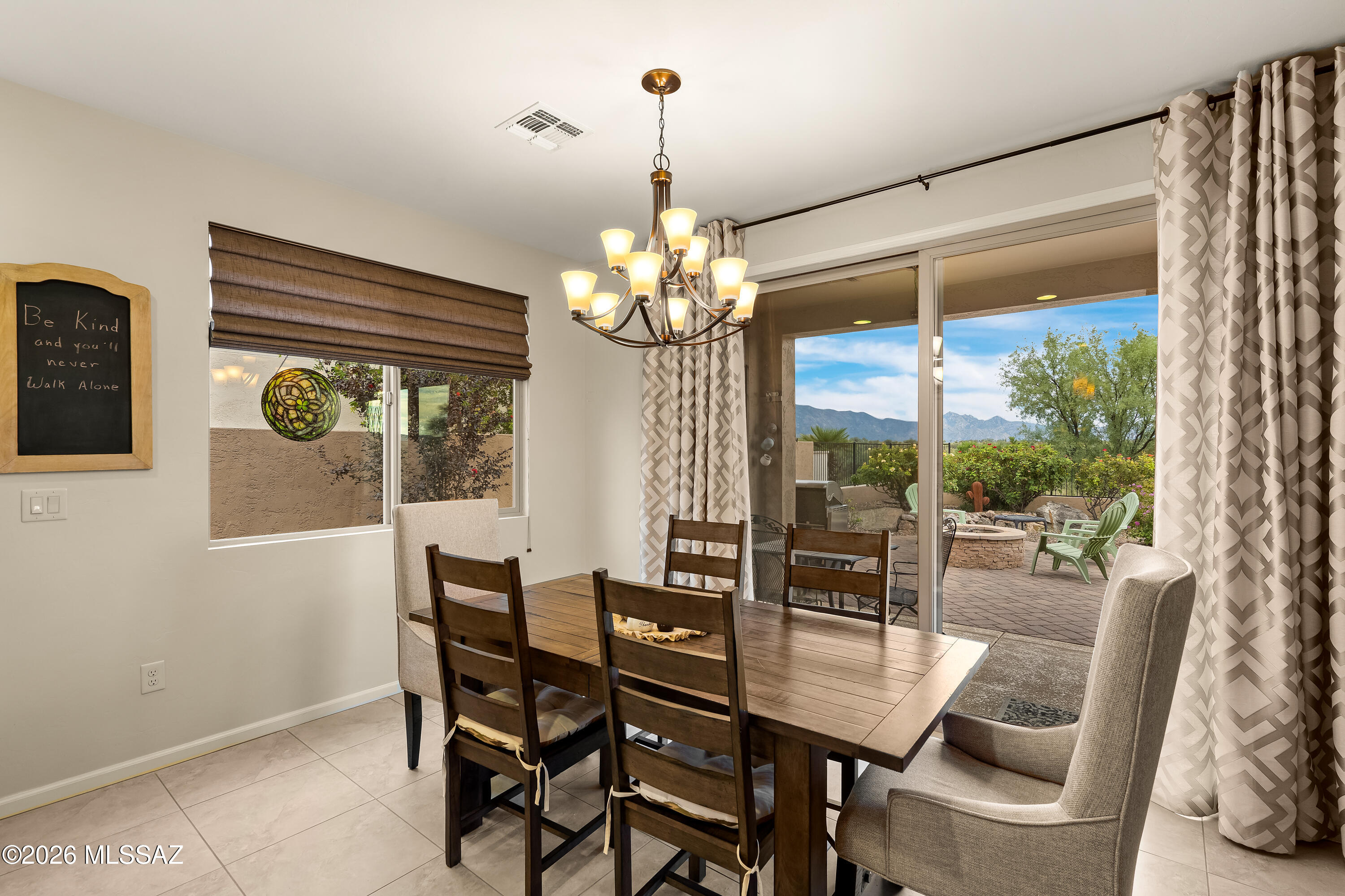 Dining room with a wood table, chandelier, and sliding doors opening to a mountain-view patio.
