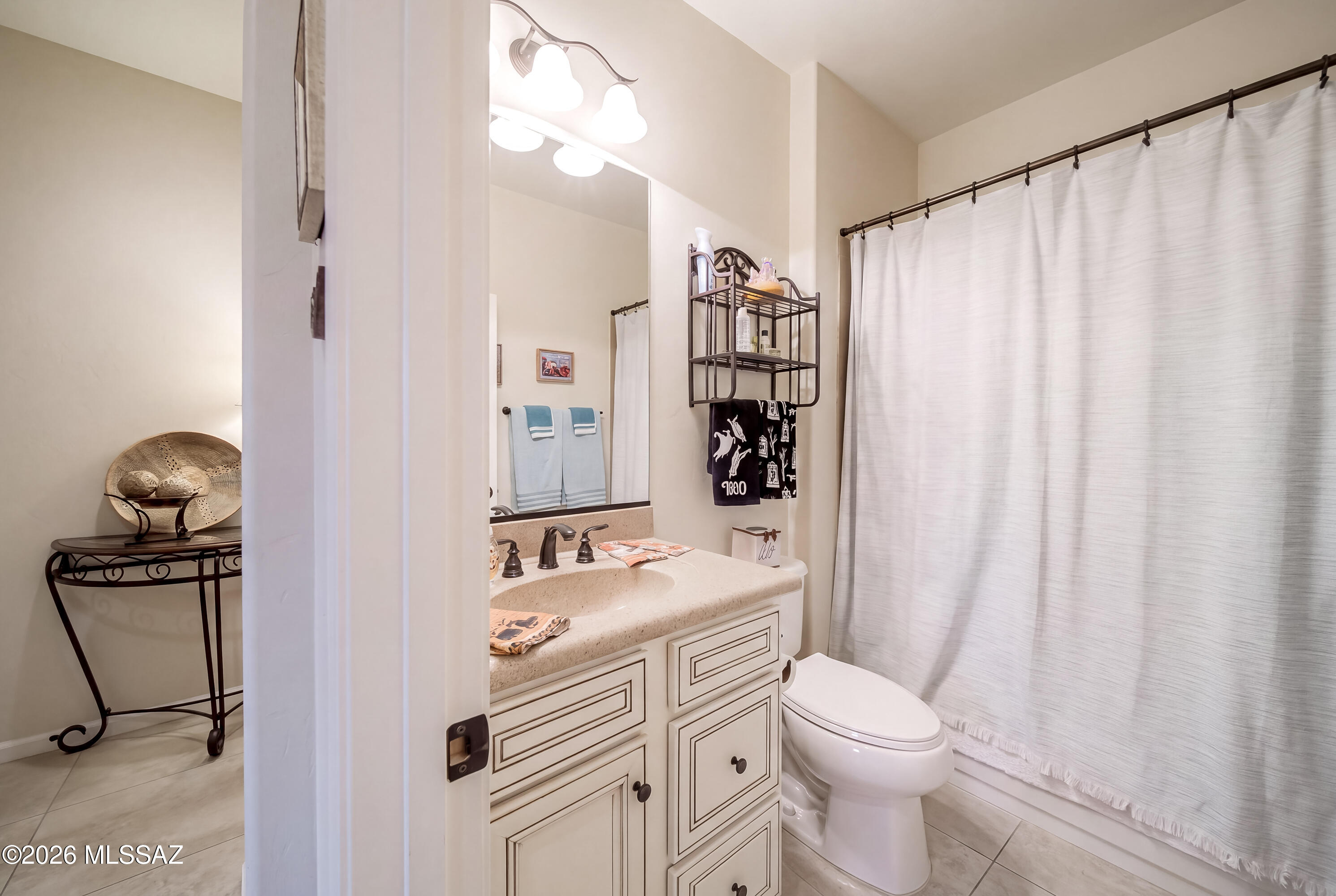 Bathroom with a cream vanity, framed mirror, white toilet, and full-length shower curtain.