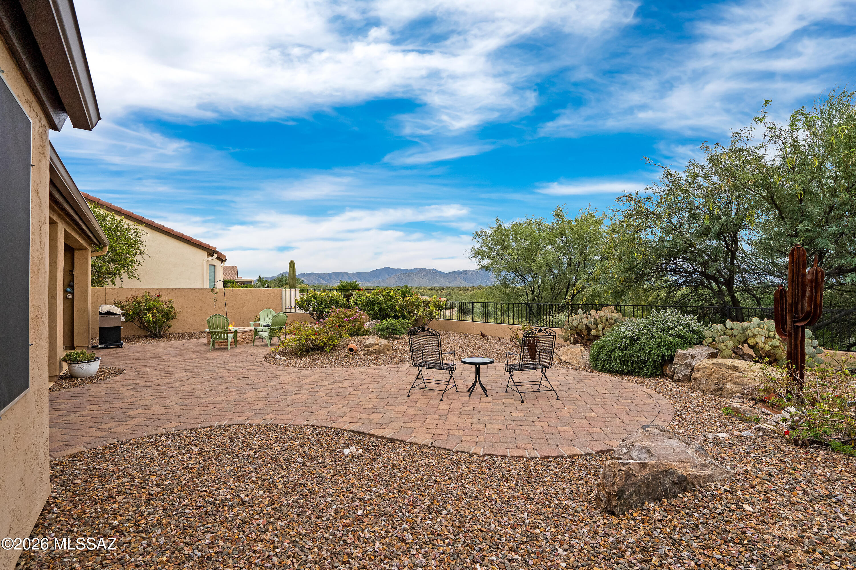 Paver patio with outdoor seating, desert landscaping, cacti, and distant mountain views.