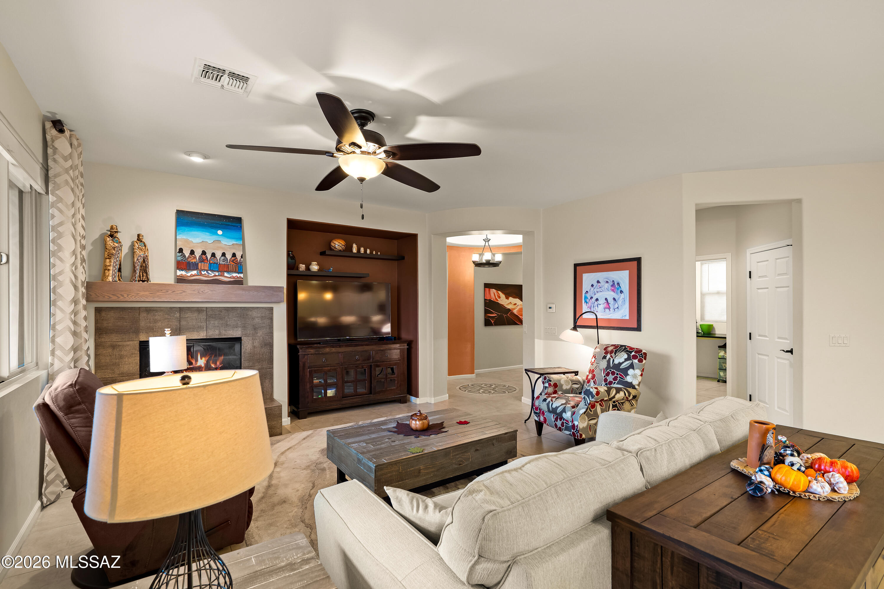 Furnished living room with a stone fireplace, built-in TV niche, and neutral sectional sofa.