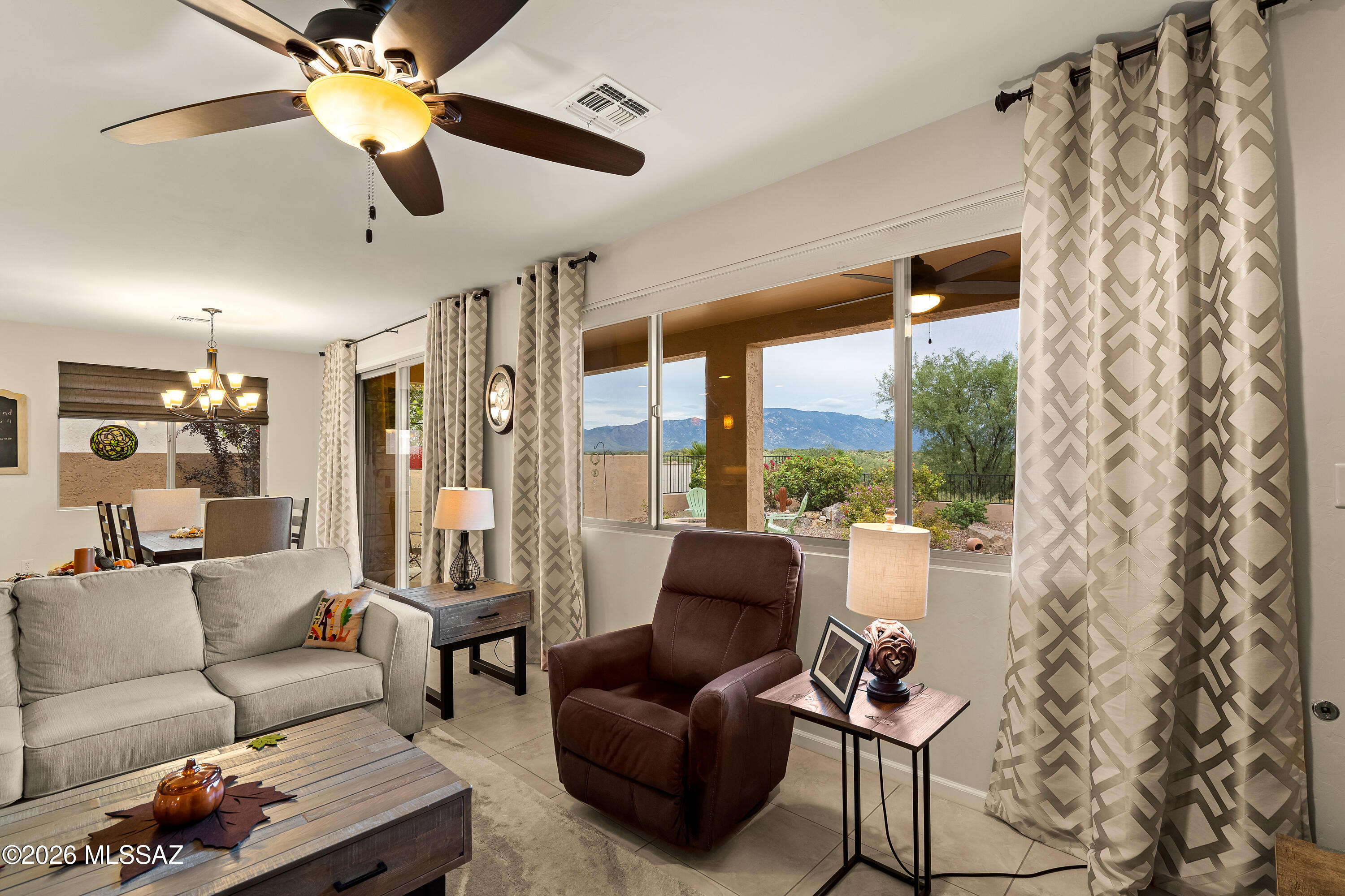 Living room with a gray sofa and recliner beside large windows overlooking mountains.