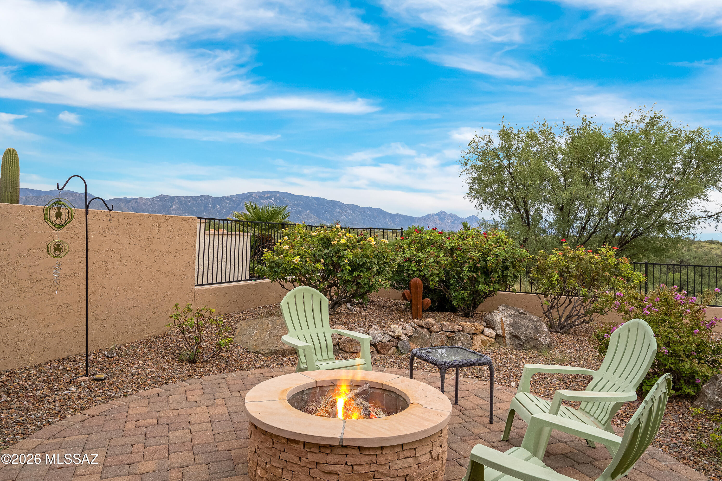 Desert patio with a round fire pit, Adirondack chairs, and mountain views.