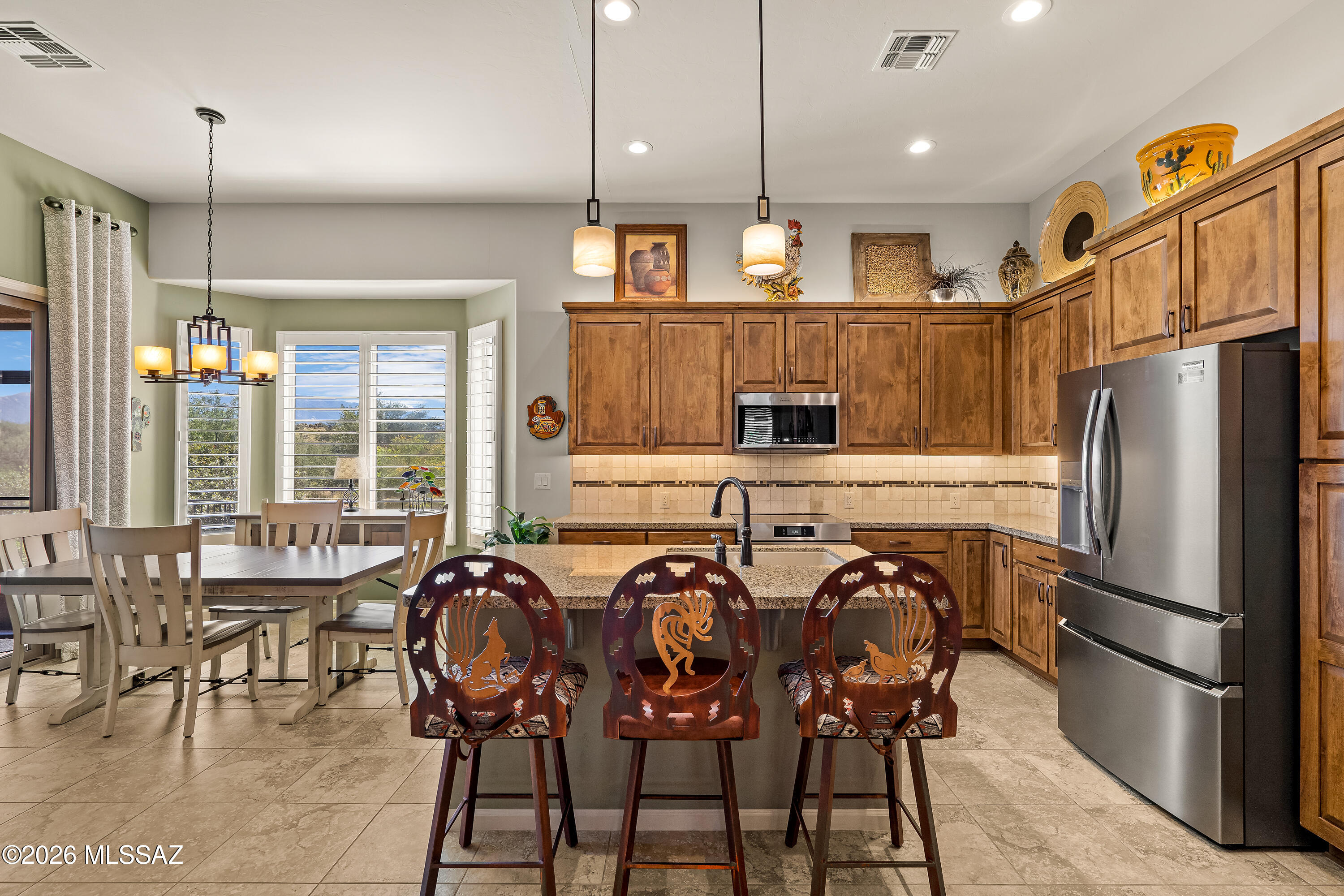 Kitchen with a granite island, carved bar stools, warm wood cabinets, and an adjoining dining area.