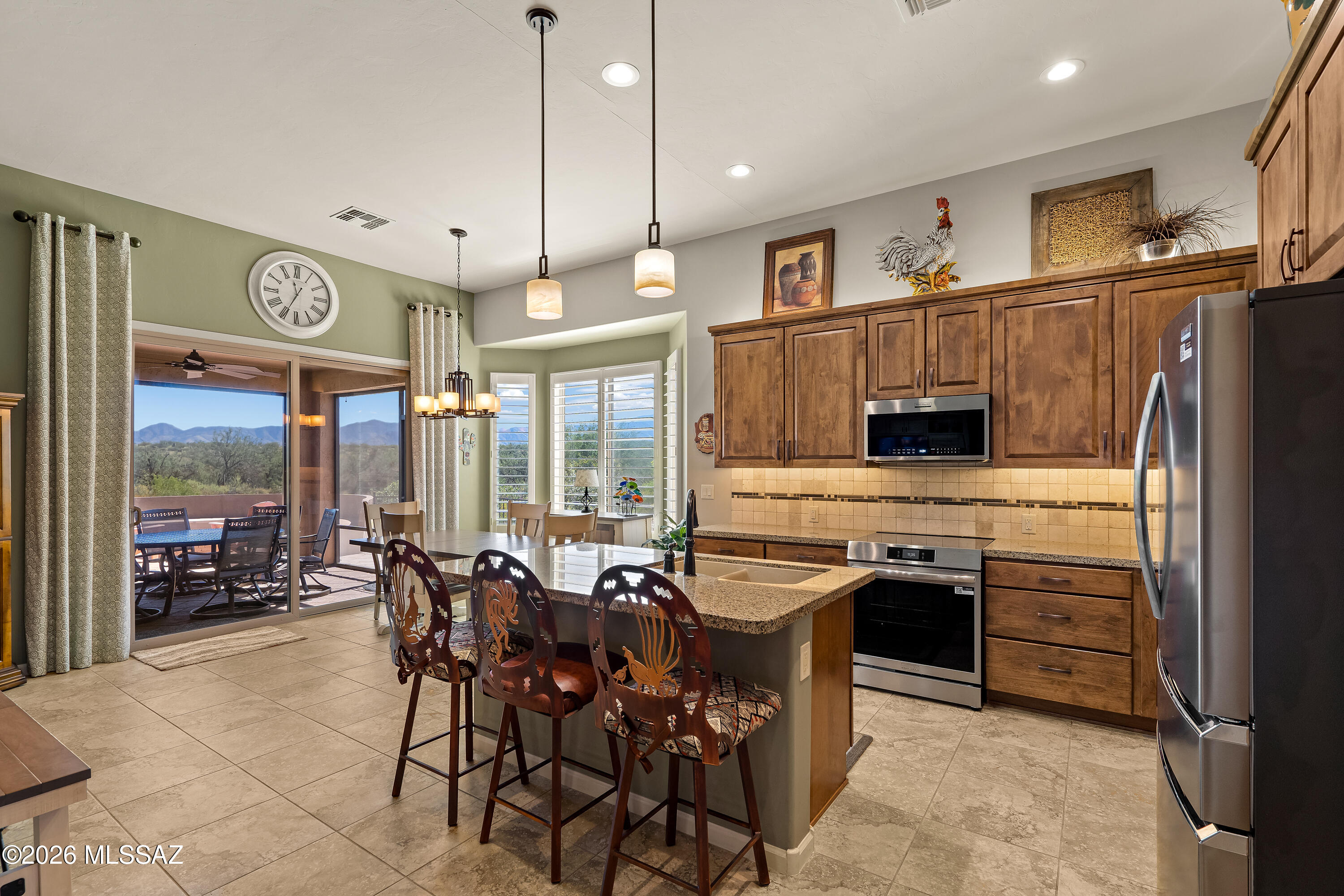 Kitchen and dining area with a granite island, wood cabinets, and mountain views through sliding glass doors.