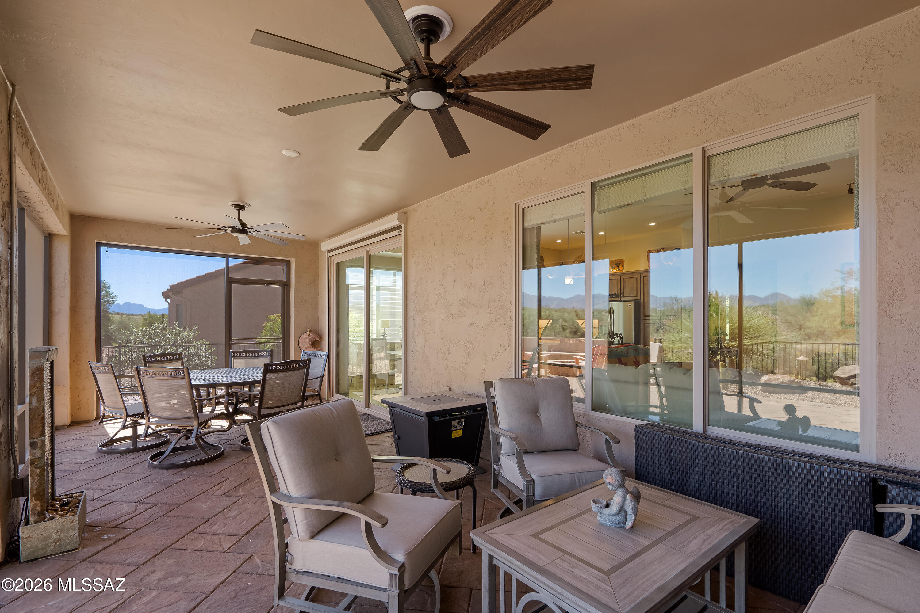 Covered patio with outdoor dining set, cushioned seating, ceiling fans, and mountain views.