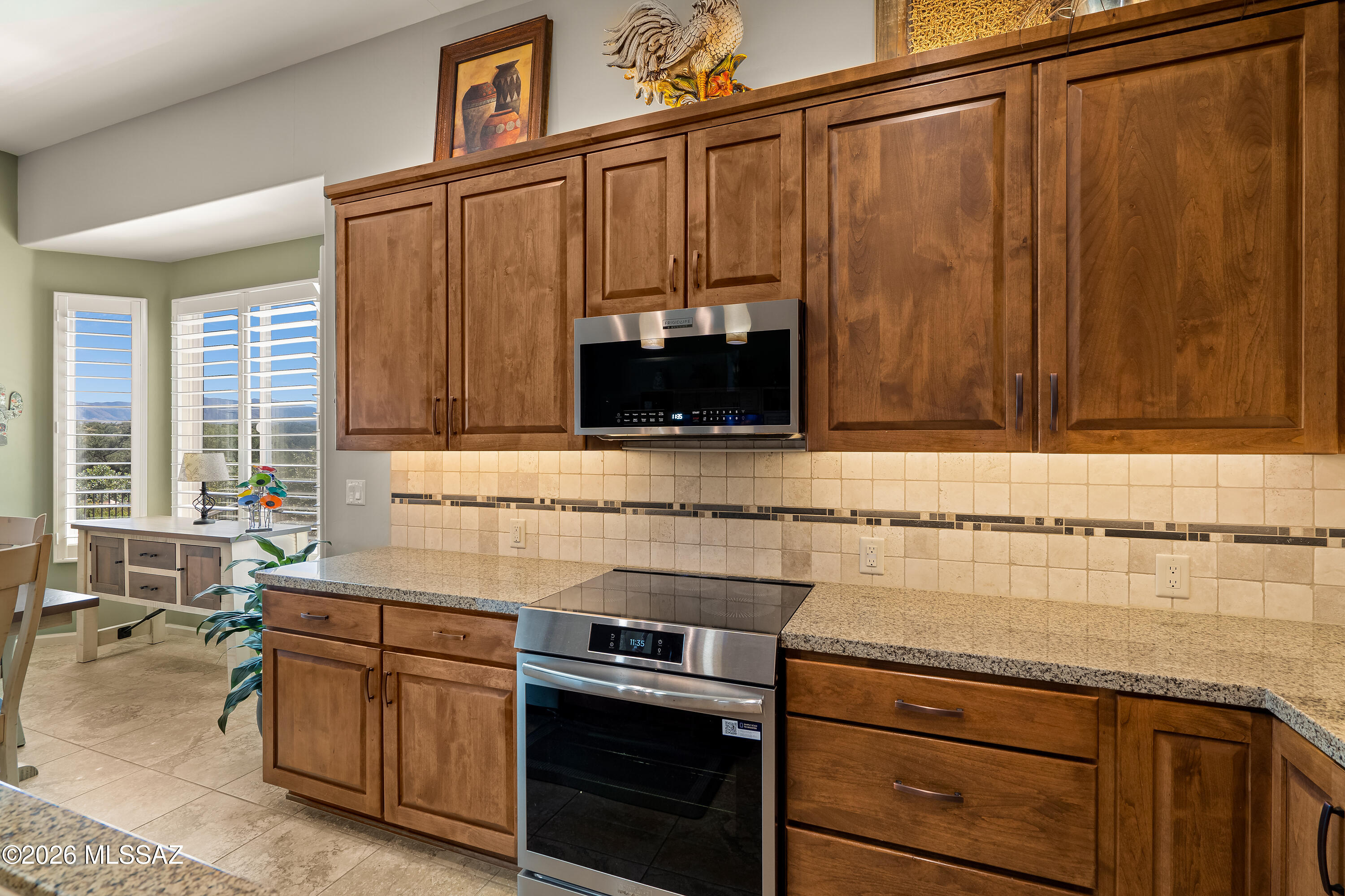 Kitchen with wood cabinetry, granite counters, stainless steel appliances, and mountain views through shuttered windows.