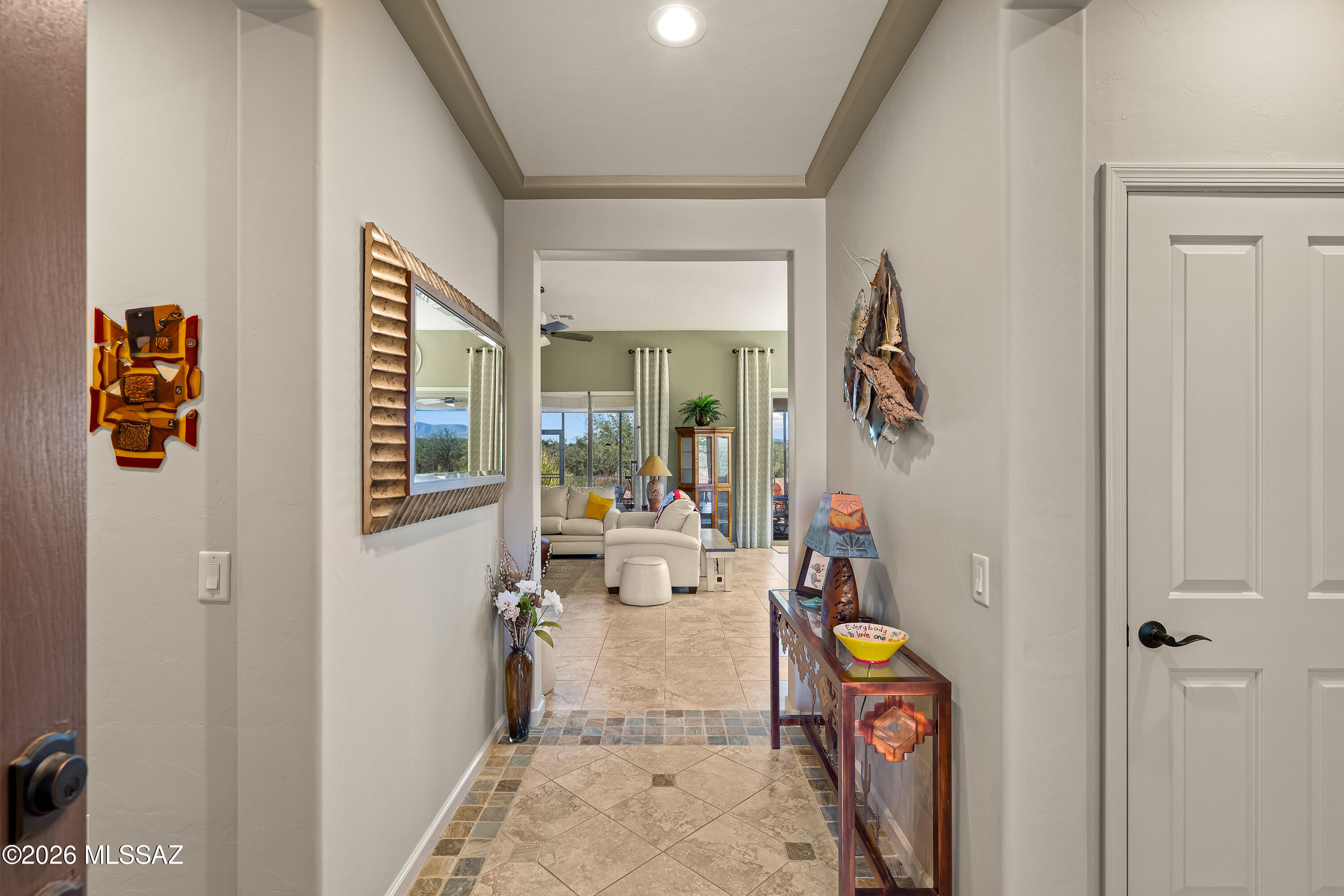 Furnished entry hallway with tiled floors, decorative mirror, and a view into the living room.