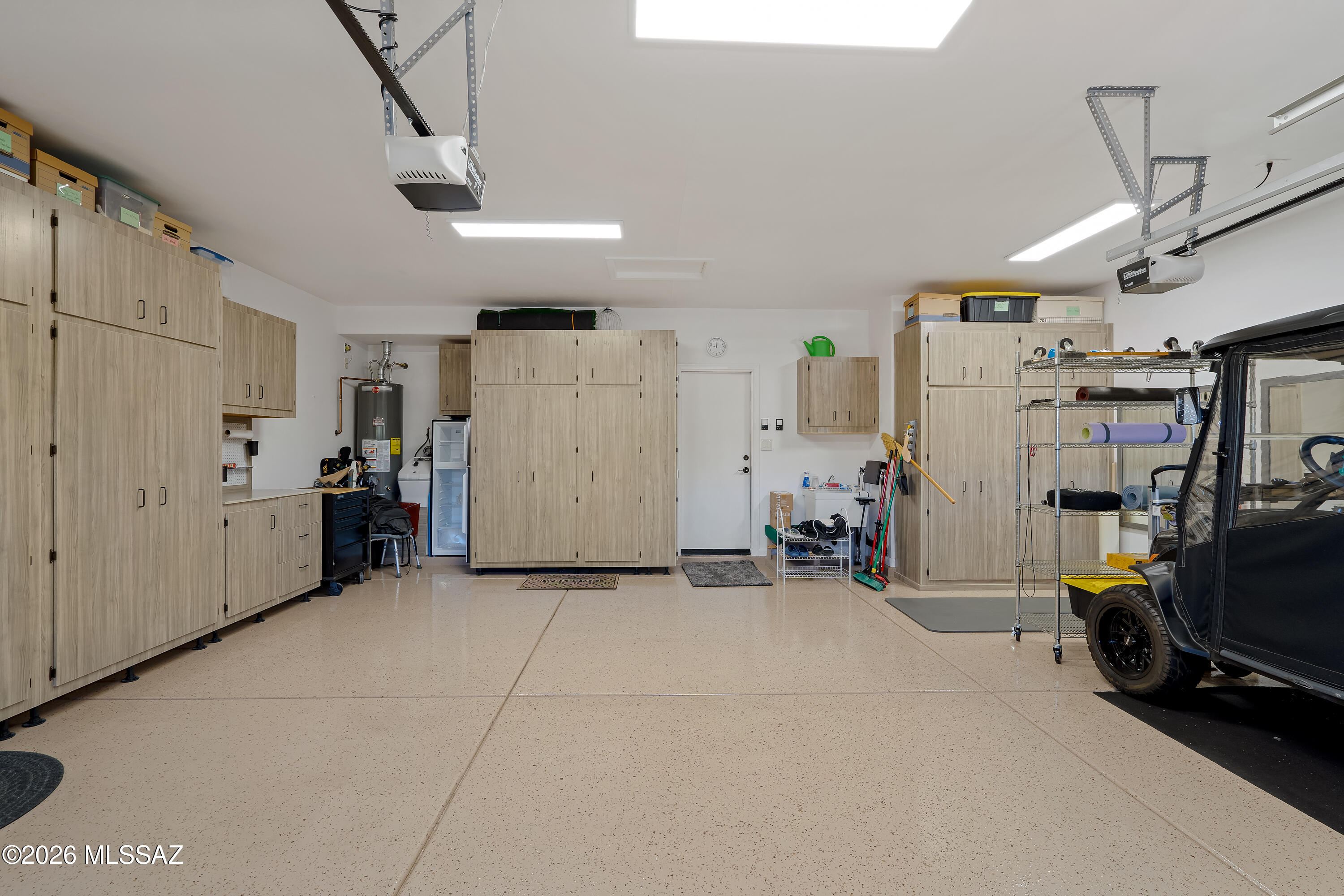 Spacious garage with extensive wood cabinetry, a speckled floor, and a utility vehicle.