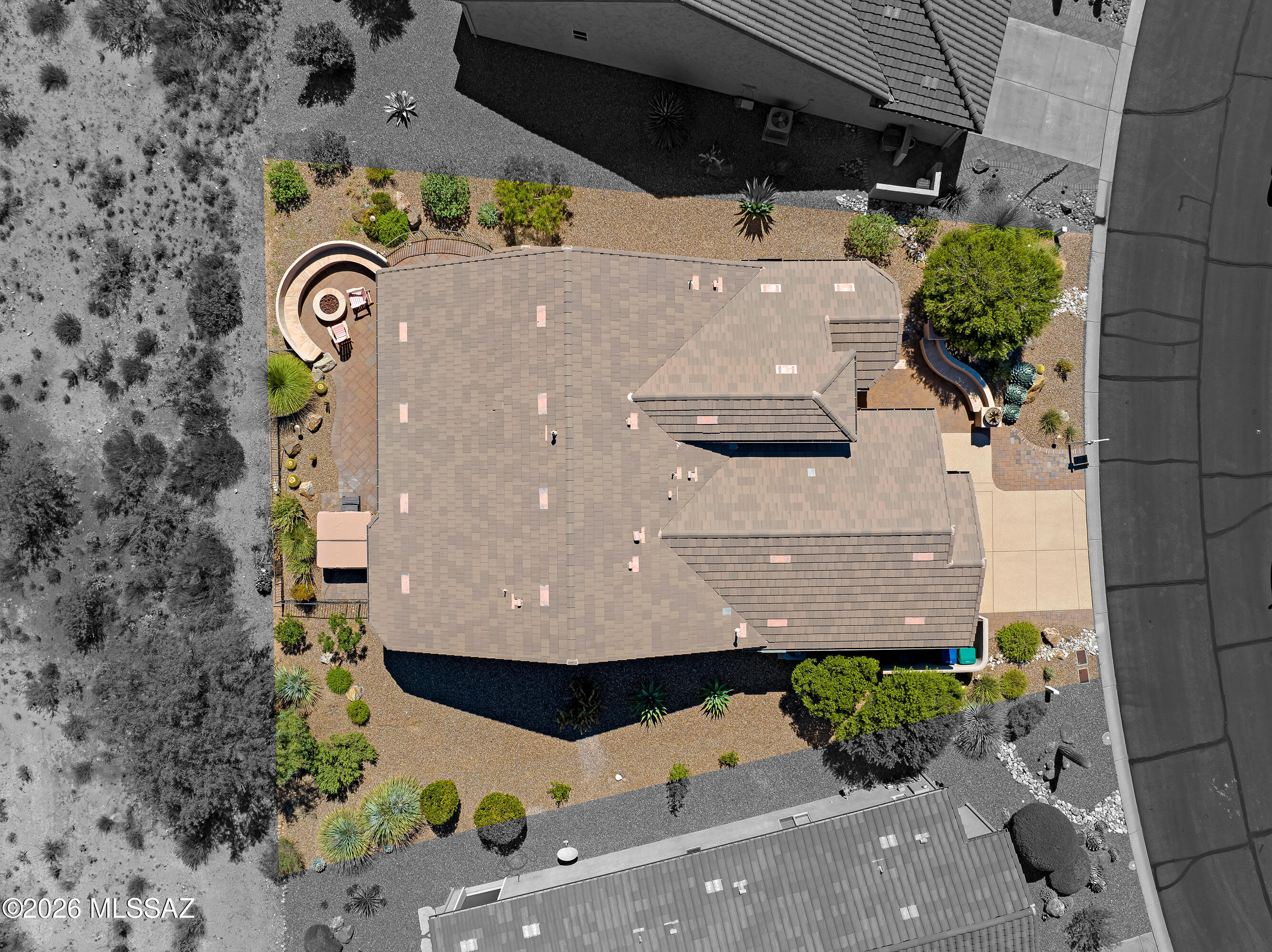 Aerial view of a desert home with a tiled roof, gravel landscaping, and a curved patio.