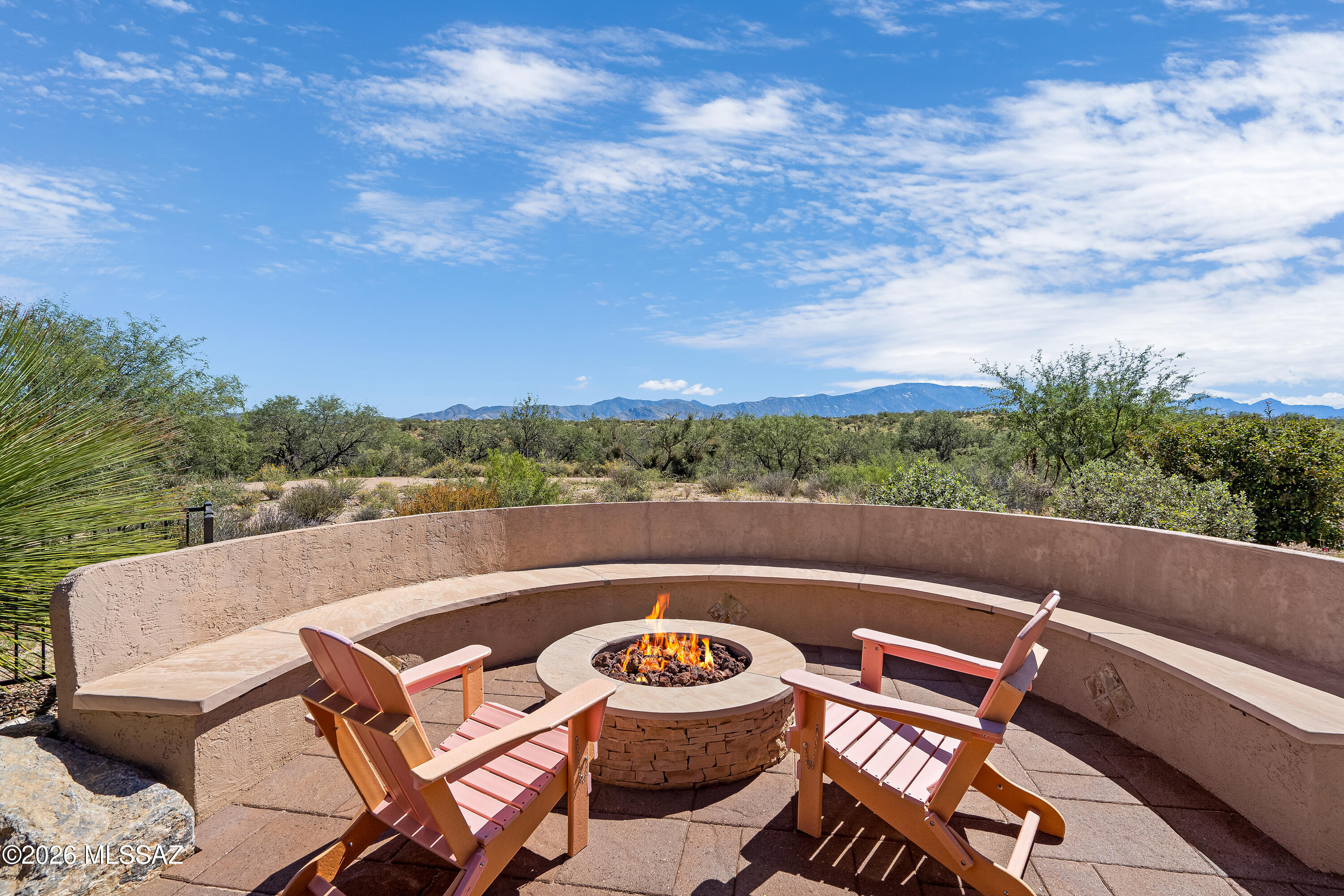 Patio fire pit and Adirondack chairs with a curved bench and distant mountain views.