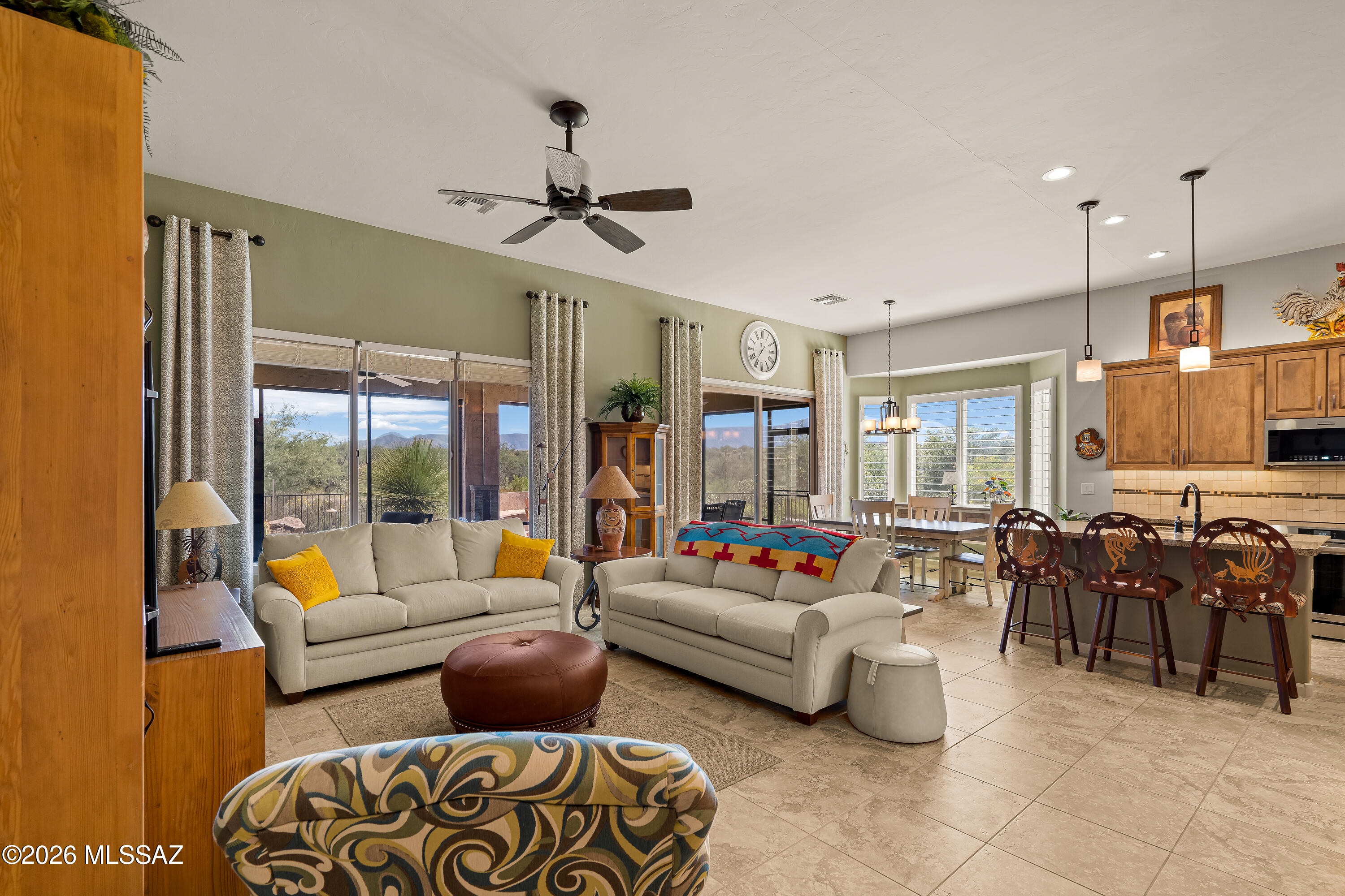 Open-plan living room with cream sofas, adjoining kitchen, and mountain views through large windows.