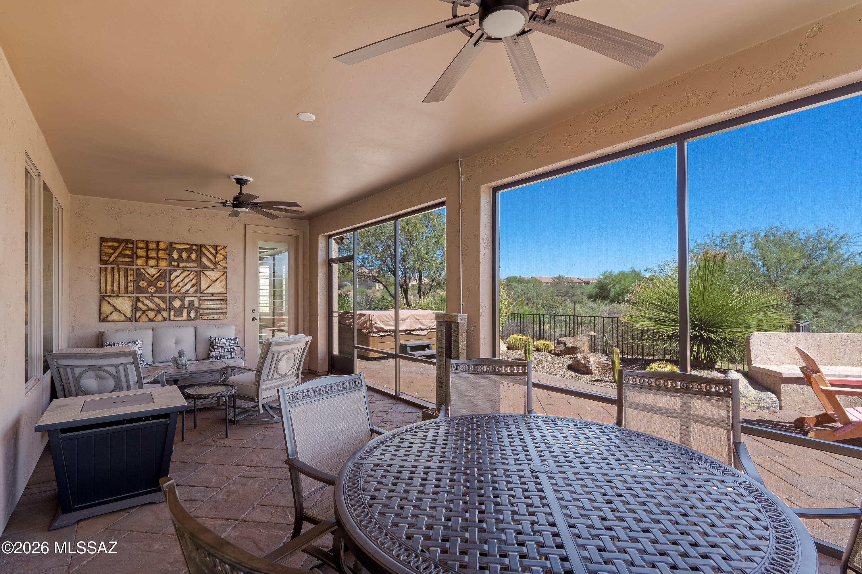 Covered patio with dining table and seating overlooking desert landscaping.