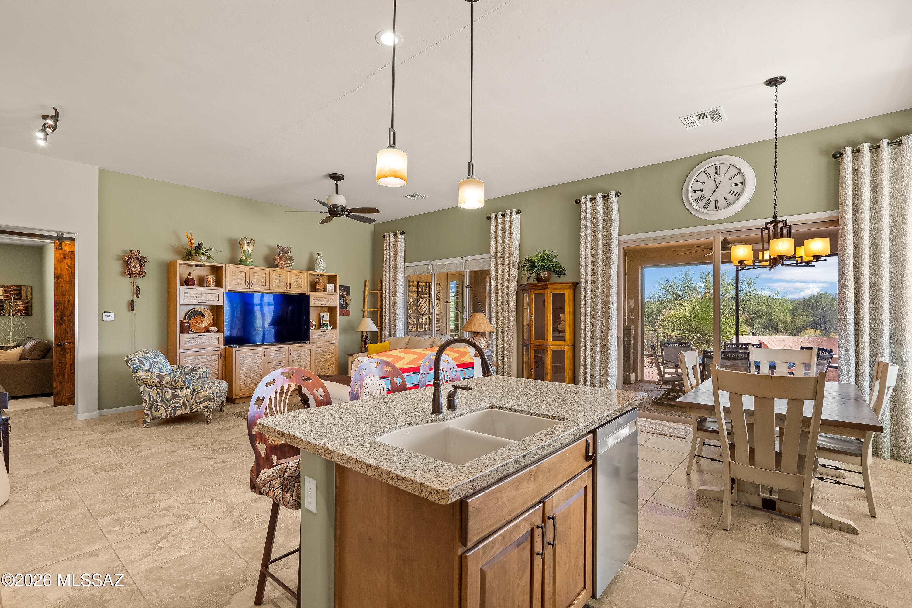 Open-plan kitchen with granite island, dining area, and sliding doors overlooking a desert patio.