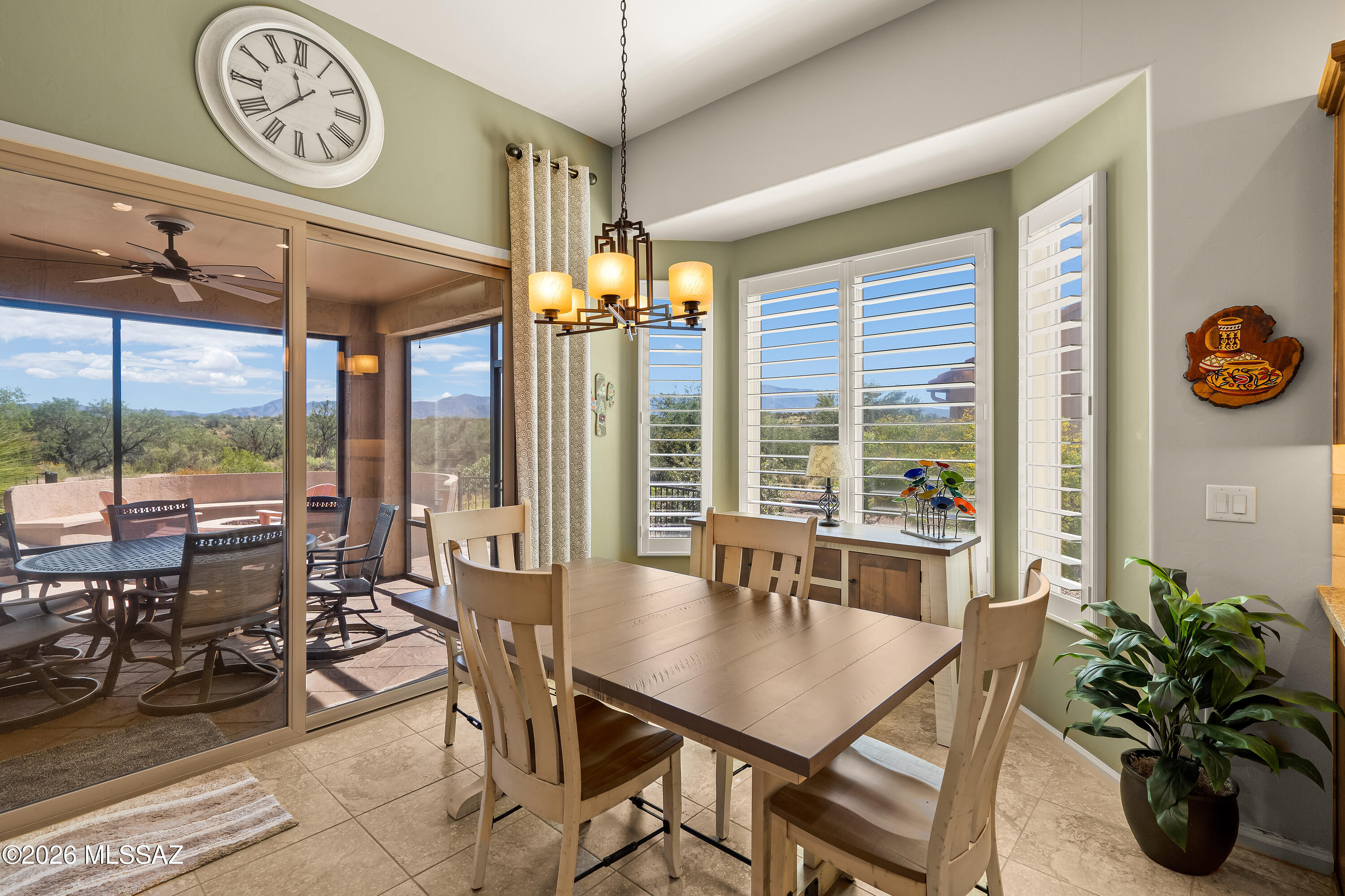 Dining room with a wooden table, plantation shutters, and sliding doors to a mountain-view patio.