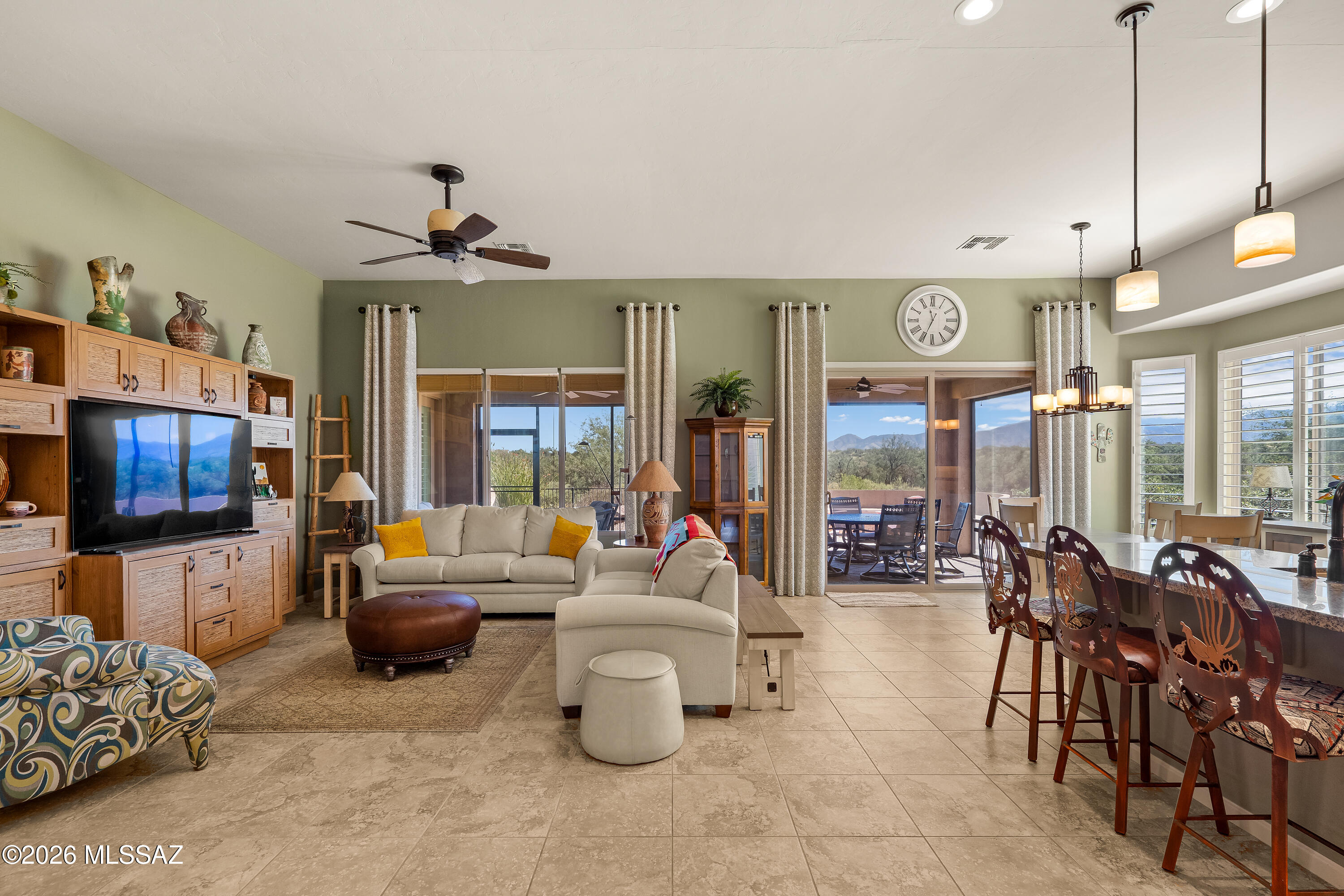 Open-plan living and dining room with a beige sectional and mountain views through sliding glass doors.