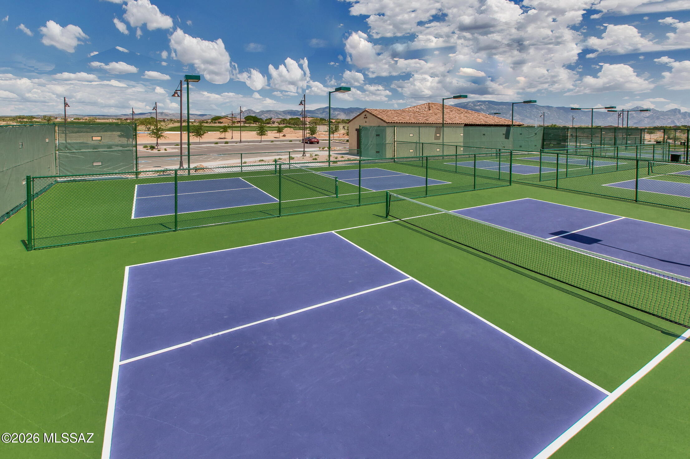 Outdoor pickleball courts with blue surfaces and mountain views.