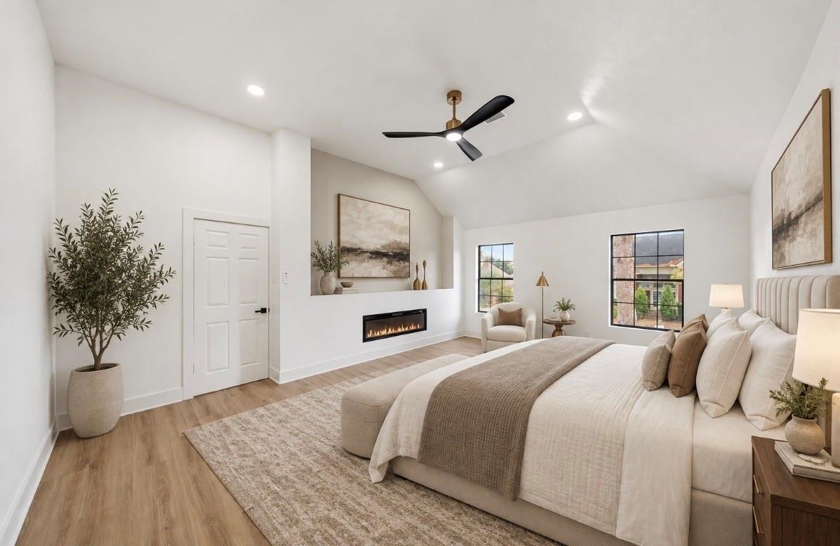 Staged bedroom with vaulted ceiling, large bed, and linear fireplace.