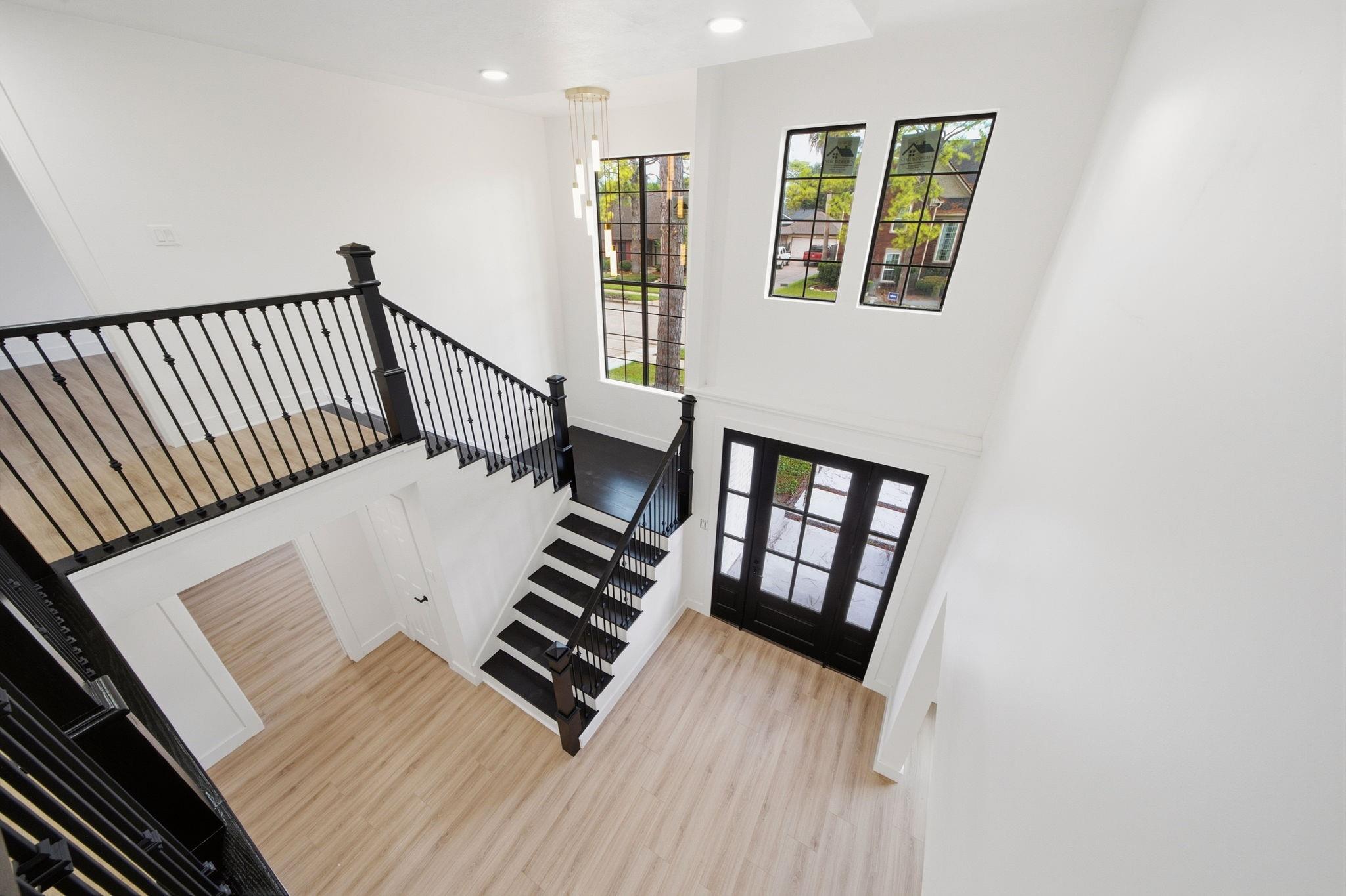 Two-story entry foyer with a black staircase, tall windows, and glass front doors.