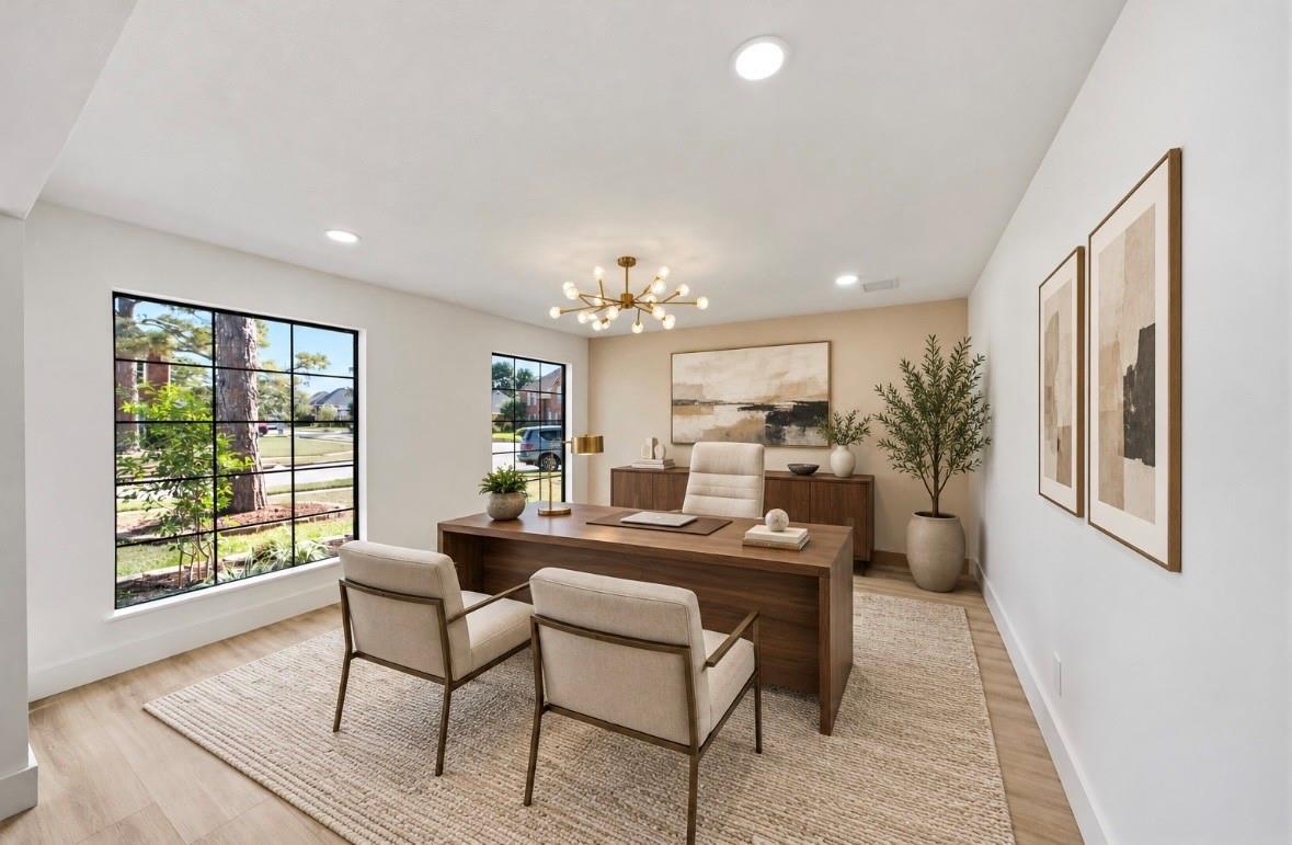 Staged home office with a dark wood desk, two guest chairs, and large street-facing windows.