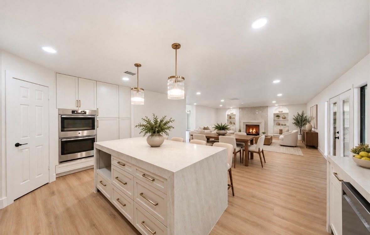 Open-plan kitchen with a large white island and adjoining living area with a fireplace.