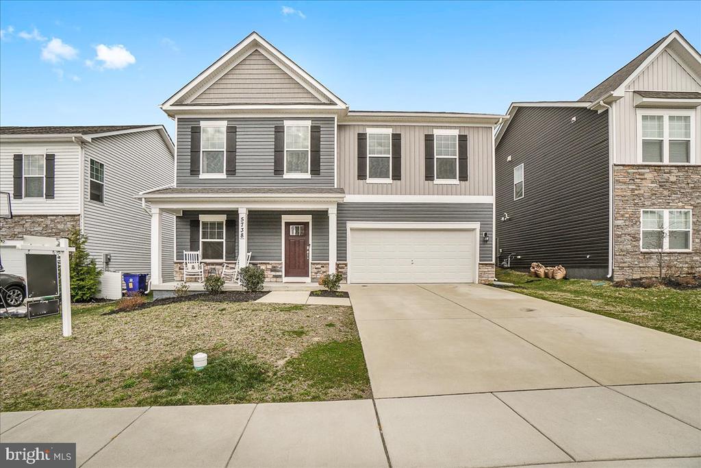 Two-story gray house with a covered porch, attached garage, and broad concrete driveway.