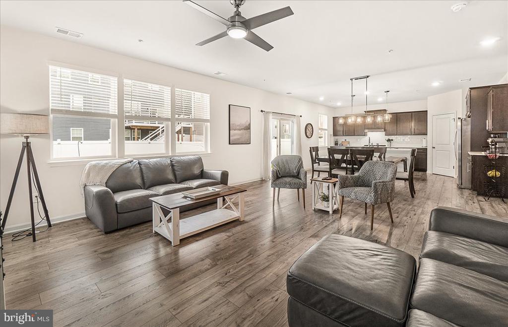 Open-plan living room with gray sofas, large windows, and dining area beside the kitchen.