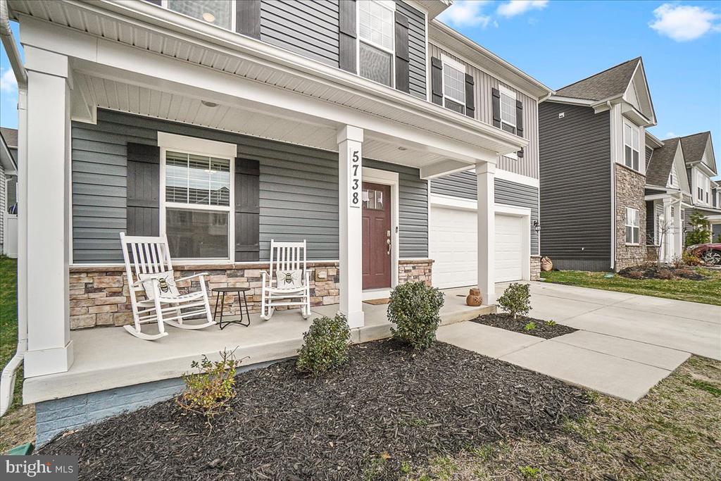 Gray two-story townhouse with covered front porch, white rocking chairs, and attached garage.