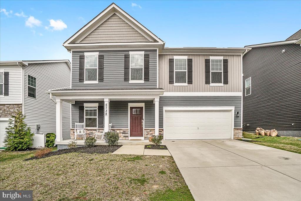 Gray two-story house with a covered porch, red front door, and attached two-car garage.