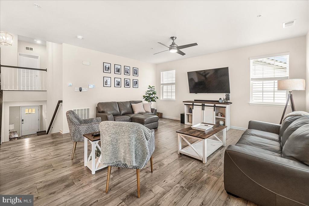 Living room with gray leather sofas, patterned chairs, and a wall-mounted television.