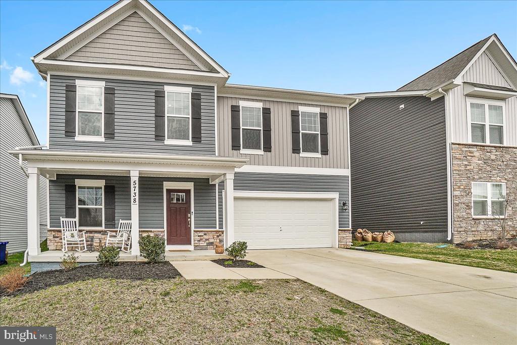 Gray two-story house with a covered porch, red front door, stone accents, and attached garage.