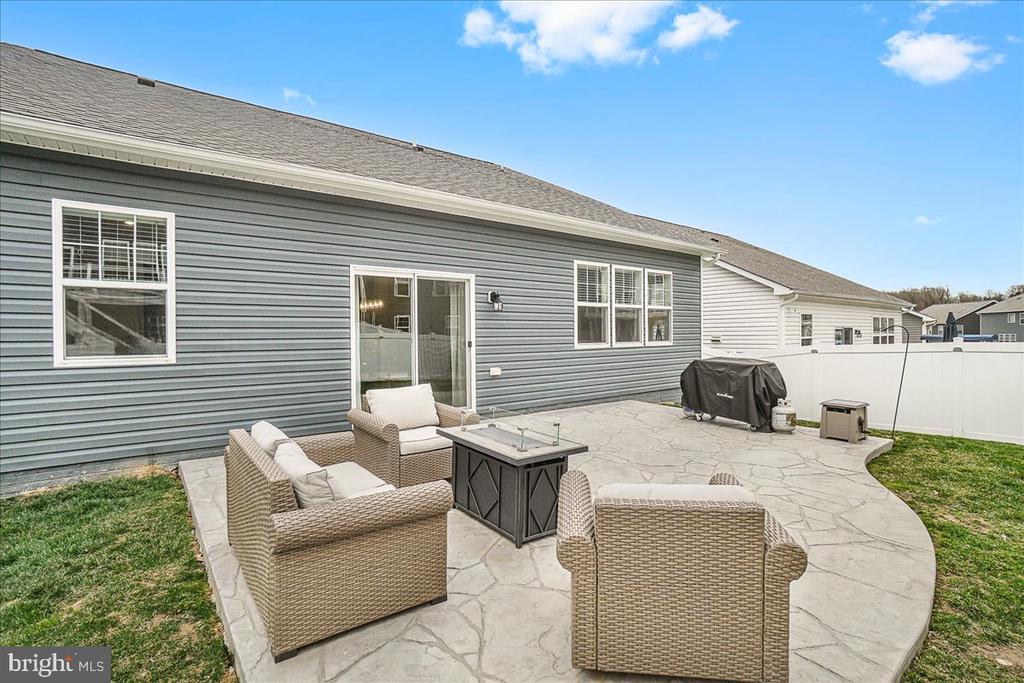 Rear patio with wicker seating and fire table beside a gray-sided house.