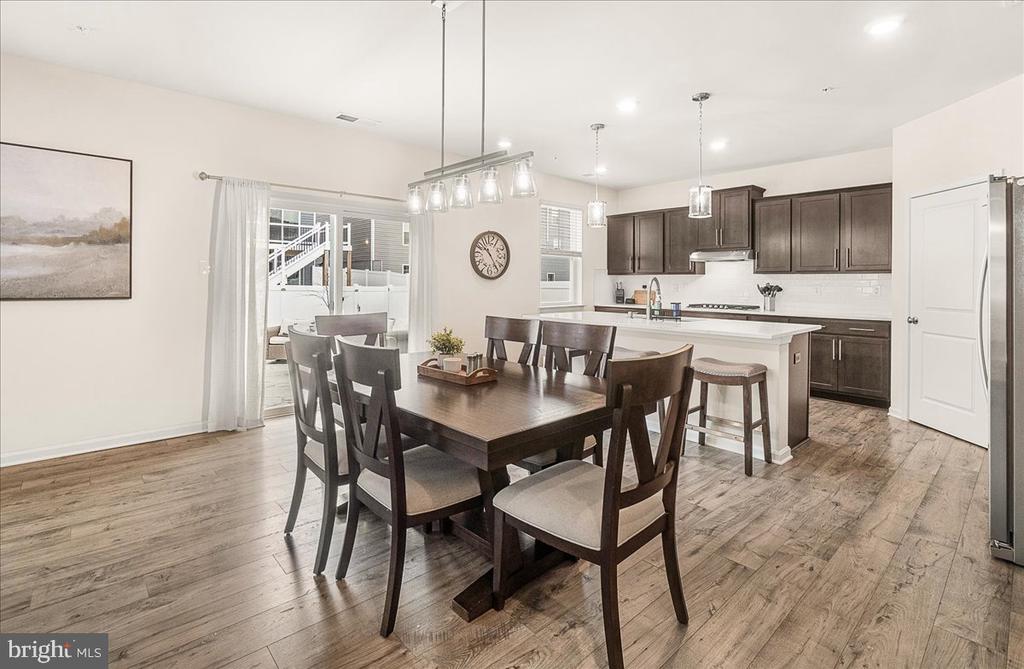 Open-plan kitchen and dining area with dark cabinets, a white island, and a large wood dining table.