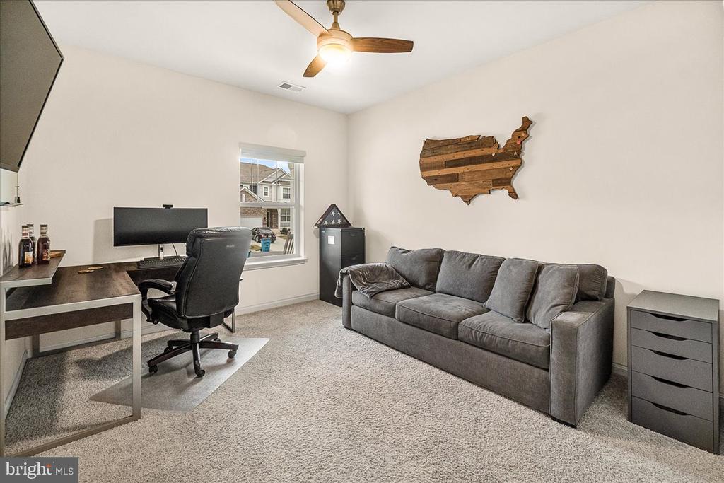Furnished home office with a gray sofa, desk, and wooden United States wall decor.