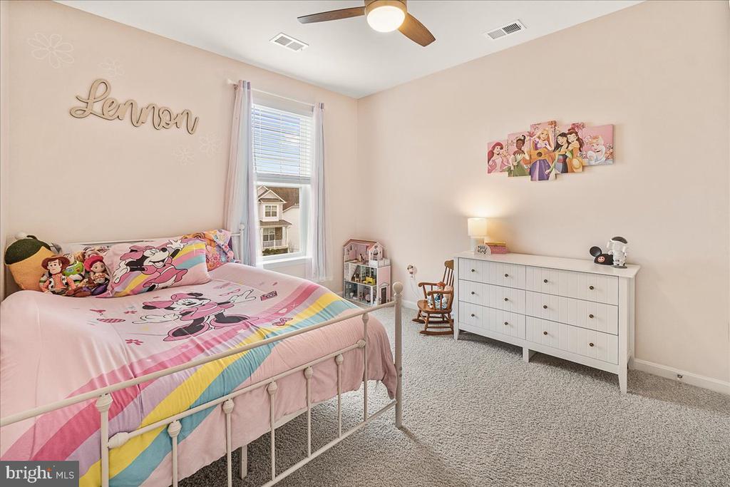 Furnished child's bedroom with pink character bedding, a white dresser, and a window.