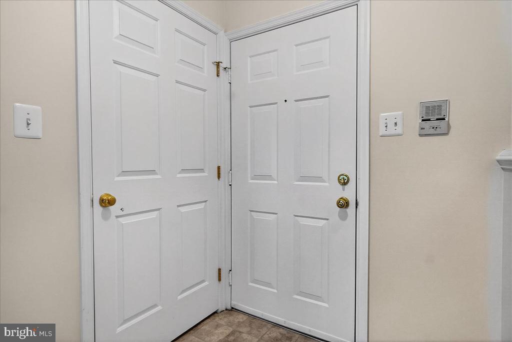 Entryway with two white paneled doors and brass hardware.