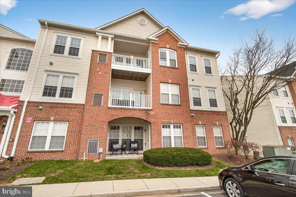 Multi-story brick and beige-sided residence with two balconies and a small ground-level patio.