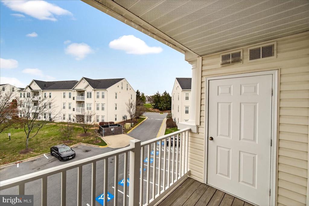 Apartment balcony overlooking nearby residential buildings and a parking area.