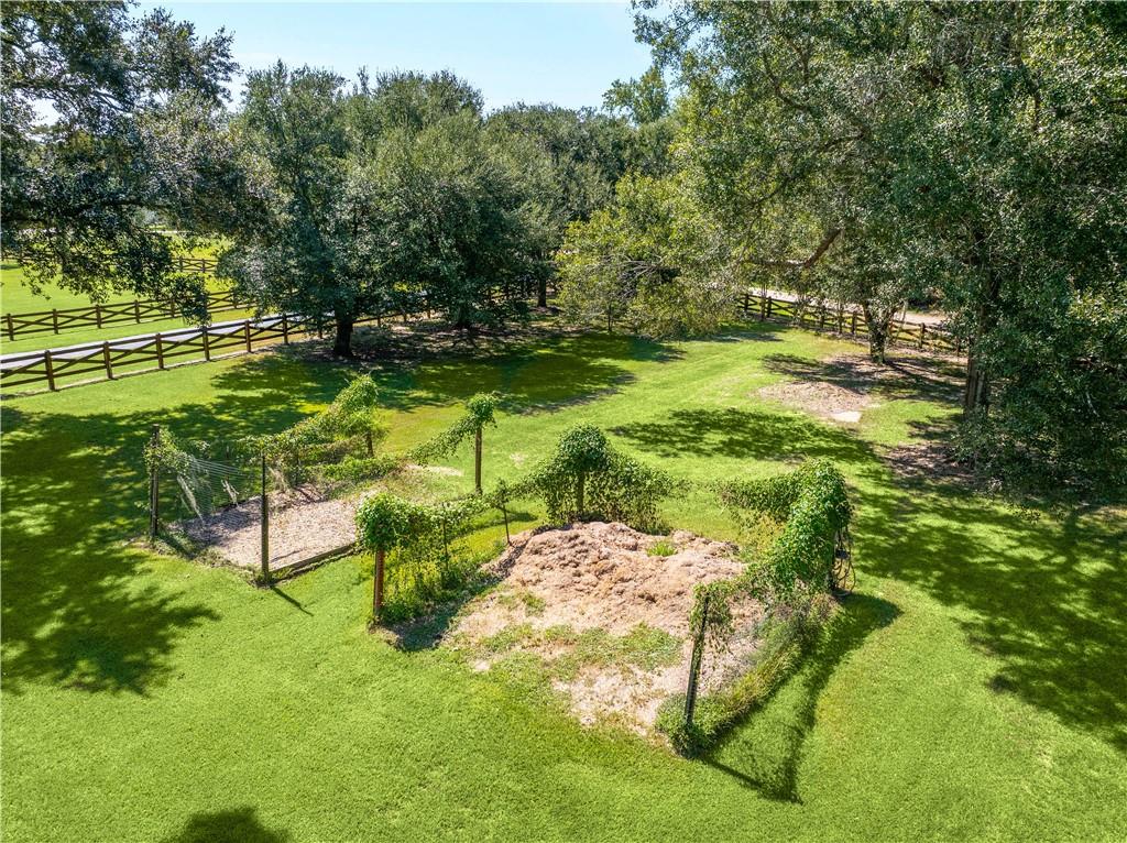Spacious tree-lined yard with wooden fencing and a small fenced garden area.