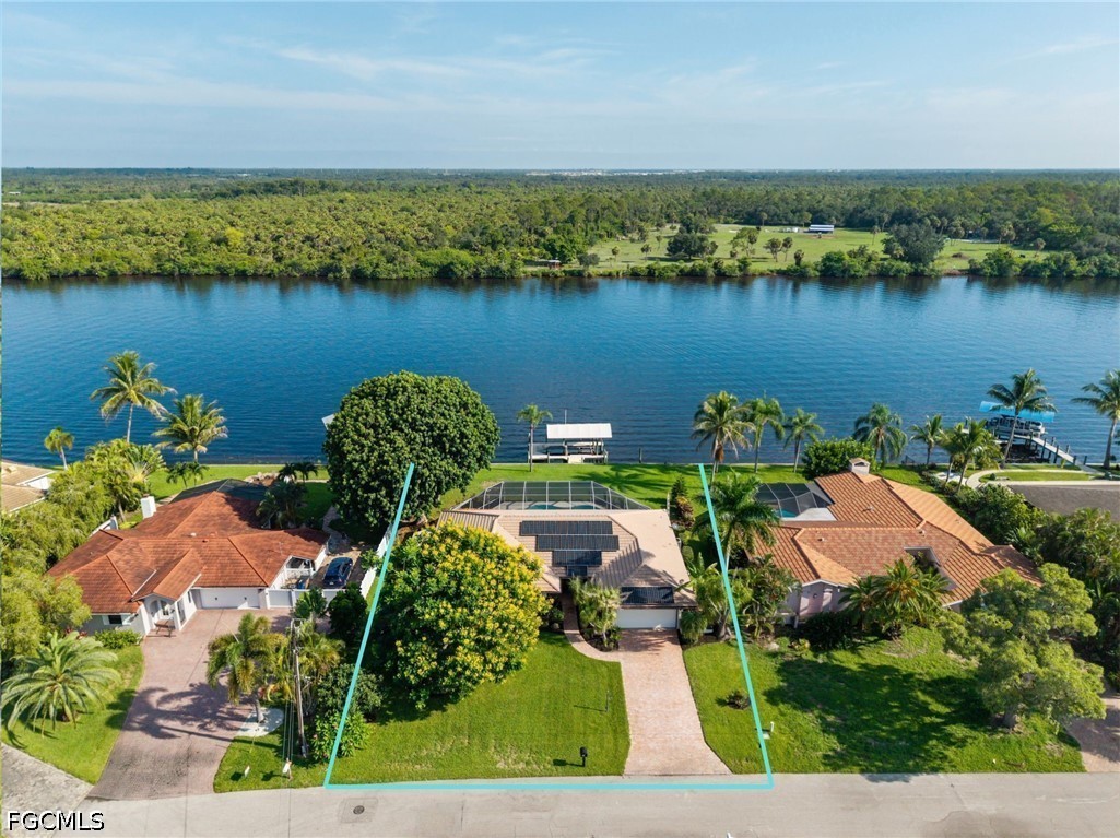 Waterfront home and outlined lot beside a broad river, with a screened pool enclosure and palm trees.