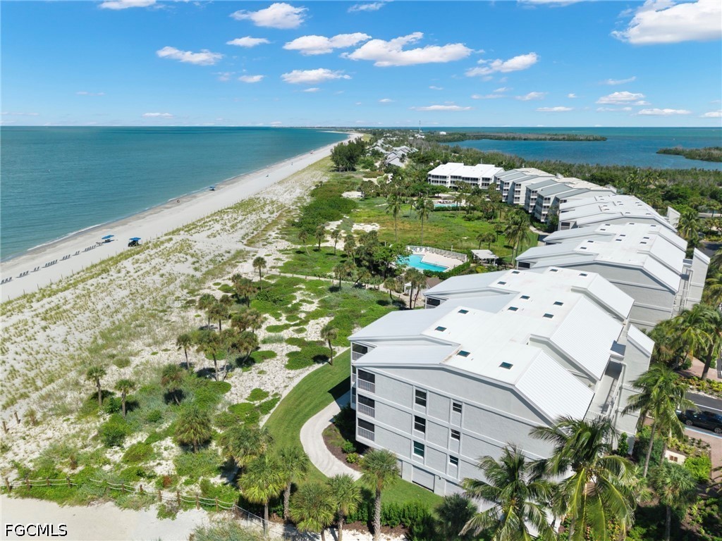 Beachfront condominiums beside a long sandy beach, with a turquoise pool and Gulf water.