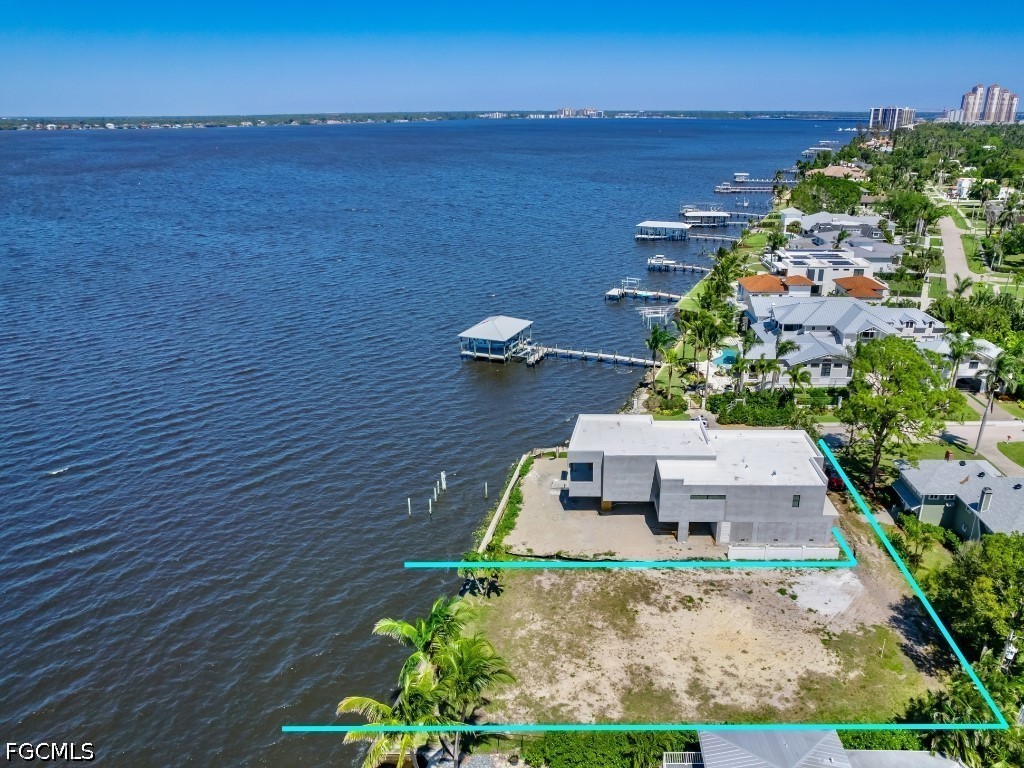 Waterfront property with a modern home under construction and turquoise lines outlining the lot beside a broad waterway.