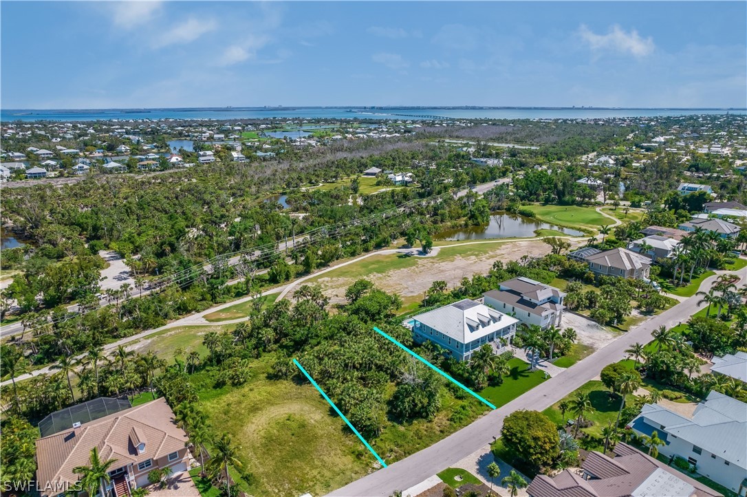 Vacant lot outlined in turquoise in a coastal neighborhood, with water visible in the distance.