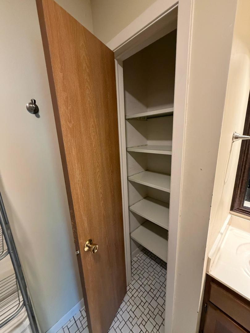 Open built-in closet with empty shelves and a small tiled floor.