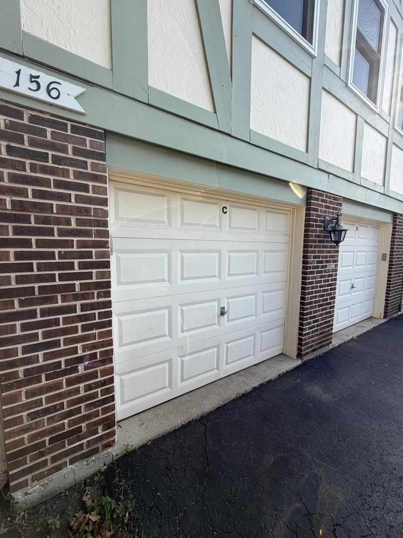Unit C’s white paneled garage door beneath the building facade, with address number 156 above.