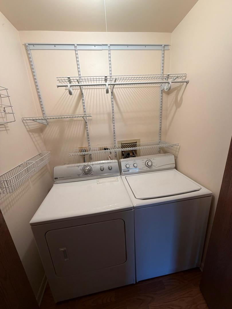 Laundry closet with side-by-side washer and dryer beneath wire storage shelves.