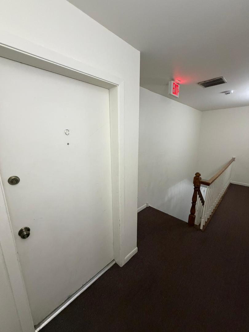 Hallway outside Unit C with a white door and stair railing.