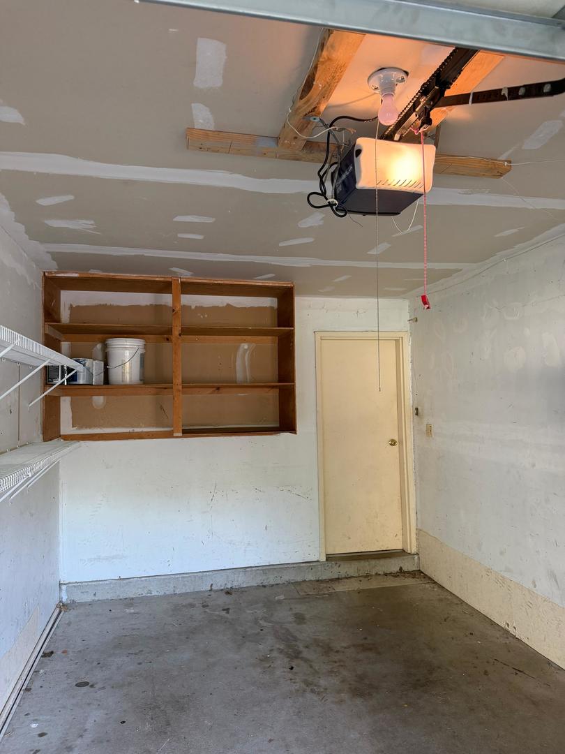 Unfinished garage with wooden storage shelves, wire shelving, and an exposed ceiling.